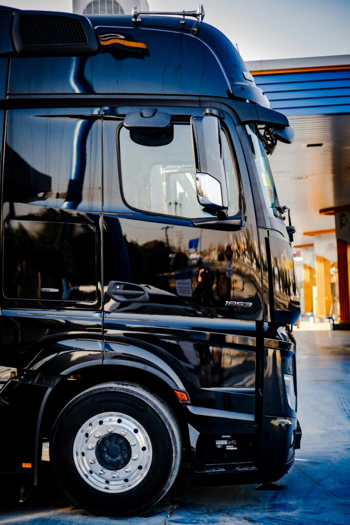 Sleek black truck parked outdoors at a service station during daytime.
